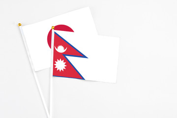 Obraz premium Nepal and Japan stick flags on white background. High quality fabric, miniature national flag. Peaceful global concept.White floor for copy space.