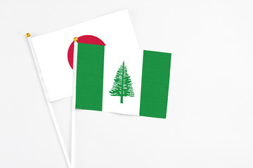 Norfolk Island and Japan stick flags on white background. High quality fabric, miniature national flag. Peaceful global concept.White floor for copy space.