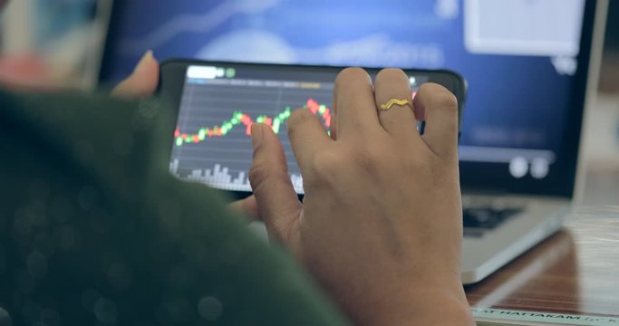 Scene of businesswoman looking at graph market data by smartphone