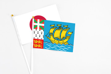 Saint Pierre And Miquelon and Japan stick flags on white background. High quality fabric, miniature national flag. Peaceful global concept.White floor for copy space.