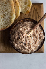 Cod liver in oil on wooden plate with bread.