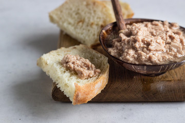 Cod liver in oil on wooden plate with bread.