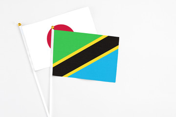 Fototapeta premium Tanzania and Japan stick flags on white background. High quality fabric, miniature national flag. Peaceful global concept.White floor for copy space.