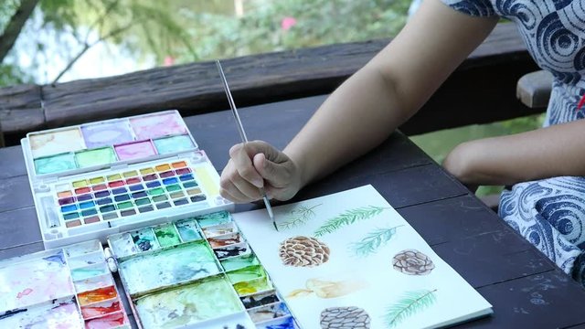 Lady is drawing pinecone using watercolor - people with Christmas celebration art hand draw watercolor concept 