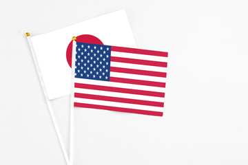 United States and Japan stick flags on white background. High quality fabric, miniature national flag. Peaceful global concept.White floor for copy space.