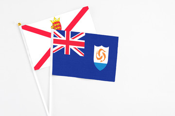 Fototapeta premium Anguilla and Jersey stick flags on white background. High quality fabric, miniature national flag. Peaceful global concept.White floor for copy space.