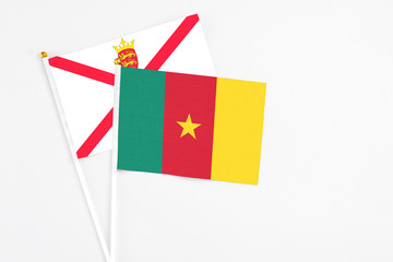 Cameroon and Jersey stick flags on white background. High quality fabric, miniature national flag. Peaceful global concept.White floor for copy space.