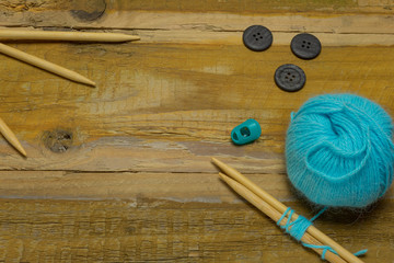 Many different kinds of wool with knitting needles and other accessories lie on an old wooden board - 302830806
