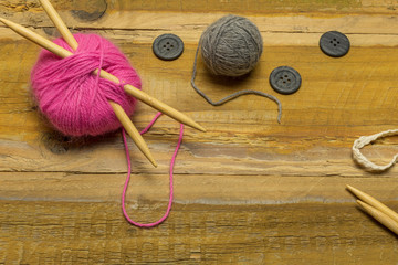 Many different kinds of wool with knitting needles and other accessories lie on an old wooden board - 302830809