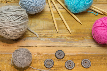Many different kinds of wool with knitting needles and other accessories lie on an old wooden board - 302830850