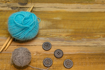 Many different kinds of wool with knitting needles and other accessories lie on an old wooden board - 302830851