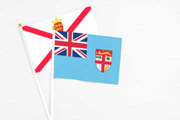 Fiji and Jersey stick flags on white background. High quality fabric, miniature national flag. Peaceful global concept.White floor for copy space.
