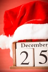 Christmas concept: 25th December wooden calendar with Christmas decorations on a red background, copy space for text