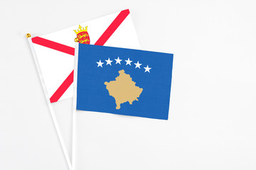 Kosovo and Jersey stick flags on white background. High quality fabric, miniature national flag. Peaceful global concept.White floor for copy space.