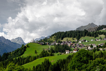 Fototapeta na wymiar View of a mountain settlement in Italy. Mountain valley of the Alps, Dolomites. Summer sunny day