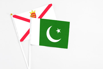 Pakistan and Jersey stick flags on white background. High quality fabric, miniature national flag. Peaceful global concept.White floor for copy space.