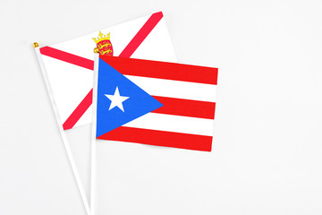 Obraz premium Puerto Rico and Jersey stick flags on white background. High quality fabric, miniature national flag. Peaceful global concept.White floor for copy space.