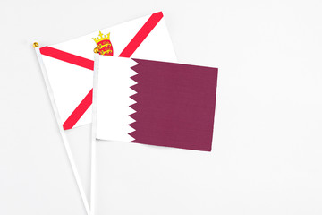 Qatar and Jersey stick flags on white background. High quality fabric, miniature national flag. Peaceful global concept.White floor for copy space.
