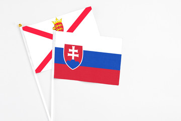 Slovakia and Jersey stick flags on white background. High quality fabric, miniature national flag. Peaceful global concept.White floor for copy space.