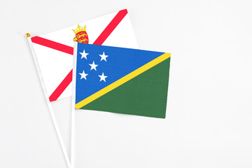 Solomon Islands and Jersey stick flags on white background. High quality fabric, miniature national flag. Peaceful global concept.White floor for copy space.