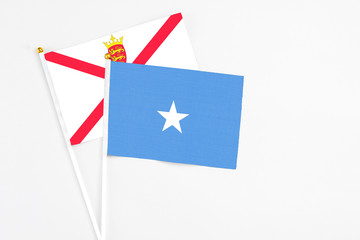 Somalia and Jersey stick flags on white background. High quality fabric, miniature national flag. Peaceful global concept.White floor for copy space.