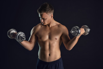 Fototapeta na wymiar Handsome male bodybuilder with dumbbells on dark background