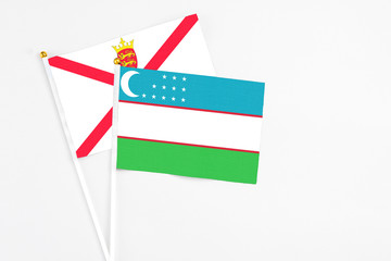 Uzbekistan and Jersey stick flags on white background. High quality fabric, miniature national flag. Peaceful global concept.White floor for copy space.