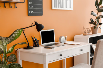 Stylish workplace with laptop near color wall