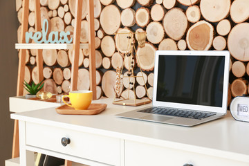 Stylish workplace with laptop near wooden wall