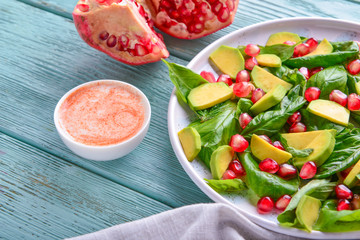 Plate with tasty avocado salad and sauce on wooden background