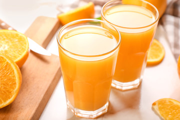 Glasses of fresh orange juice on light table