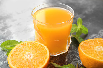 Glass of fresh orange juice with mint on dark background