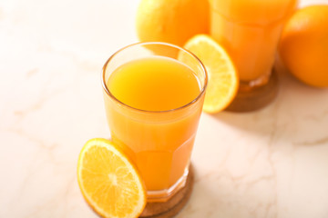 Glass of fresh orange juice on white table