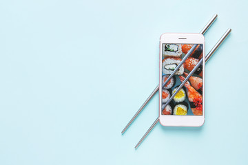 Téléphone portable avec sushi à l& 39 écran et baguettes sur fond de couleur