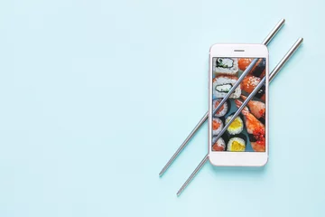 Fotobehang Mobiele telefoon met sushi op het scherm en eetstokjes op gekleurde achtergrond © Pixel-Shot