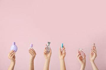 Female hands with different perfume bottles on color background