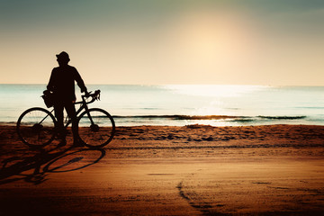Obraz premium Silhouette of cyclist on the beach at sunset.