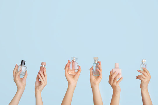 Female hands with different perfume bottles on color background