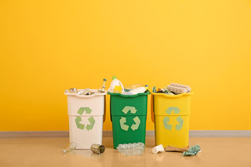 Containers with different types of garbage near color wall. Recycling concept