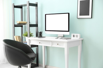 Comfortable workplace with modern computer near color wall
