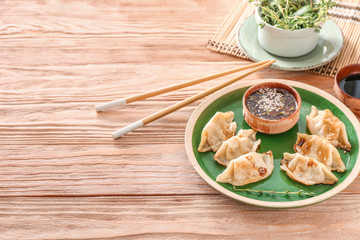 Plate with tasty Japanese gyoza and sauce on wooden table