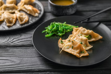Plate with tasty Japanese gyoza on wooden table