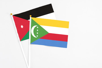 Comoros and Jordan stick flags on white background. High quality fabric, miniature national flag. Peaceful global concept.White floor for copy space.