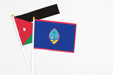 Guam and Jordan stick flags on white background. High quality fabric, miniature national flag. Peaceful global concept.White floor for copy space.