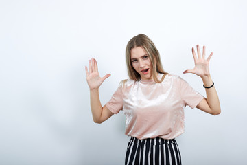 Fototapeta na wymiar Surprised cheerful young woman in casual shirt, looking camera, spreading hands isolated on white background in studio. People sincere emotions, lifestyle concept.