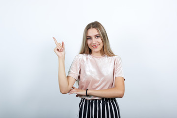 Attractive young unshaven woman in casual shirt showing on workspace isolated on white wall...