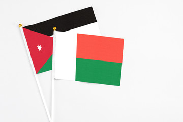 Madagascar and Jordan stick flags on white background. High quality fabric, miniature national flag. Peaceful global concept.White floor for copy space.