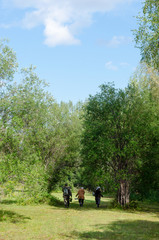 Naklejka premium Yakut women and men walk on the green grass in the field of the Northern forest of Yakutia in the afternoon.