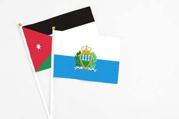 San Marino and Jordan stick flags on white background. High quality fabric, miniature national flag. Peaceful global concept.White floor for copy space.