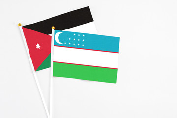 Uzbekistan and Jordan stick flags on white background. High quality fabric, miniature national flag. Peaceful global concept.White floor for copy space.
